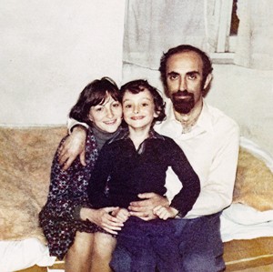 photo of smiling child sitting between parents on sofa