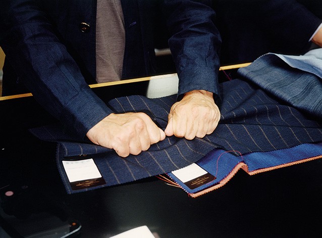 photo of two hands scrunching a pinstripe navy fabric sample into fists