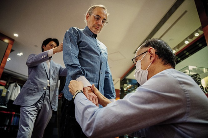 photo of Gary getting his shirt fitted as someone knees to adjust the cuff and another man adjusts the back