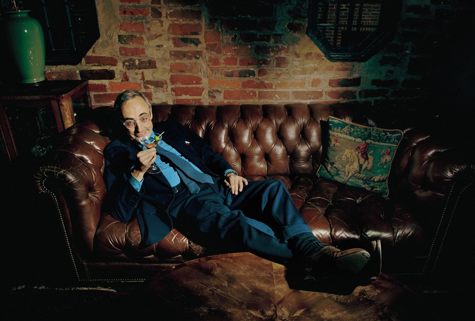 photo of author reclining on dark brown leather couch raising a martini glass in his right hand