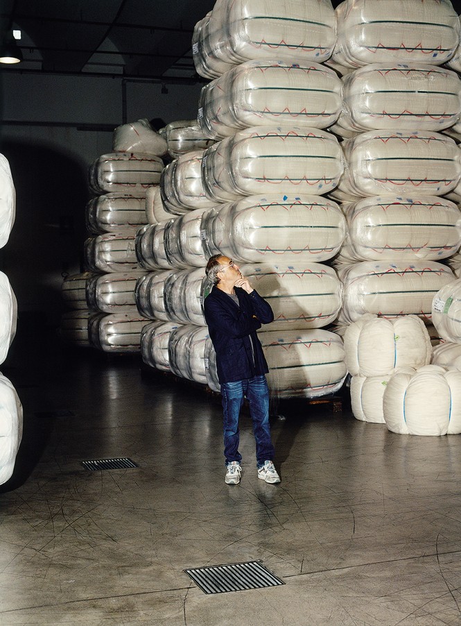 photo of author standing in warehouse next to piles of baled wool 3 times as tall as he is