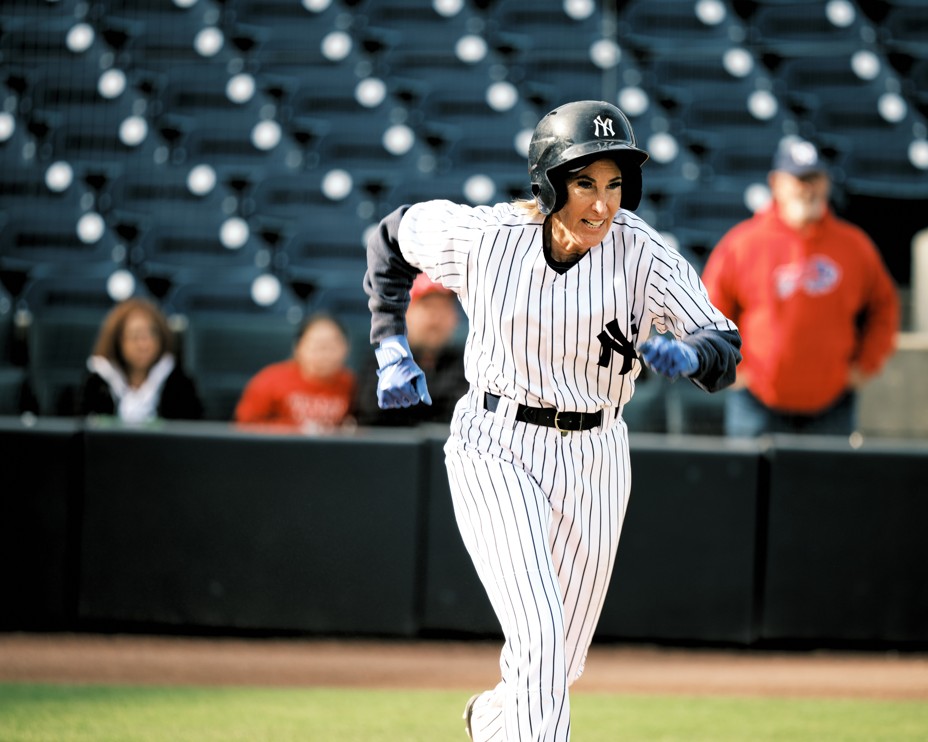 photo of woman in baseball uniform and batting helmet running on field