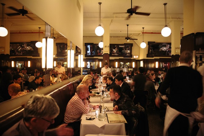 Diners at a long table in a dimly lit restaurant.