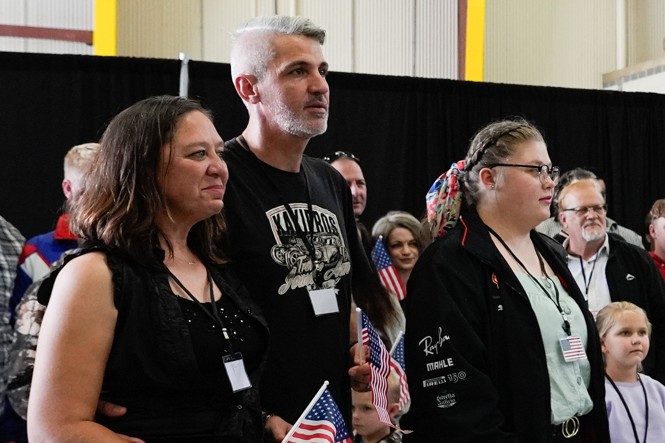 A group of people stand together. Some hold American flags
