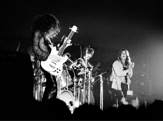 In a black and white photo, Black Sabbath performs on stage