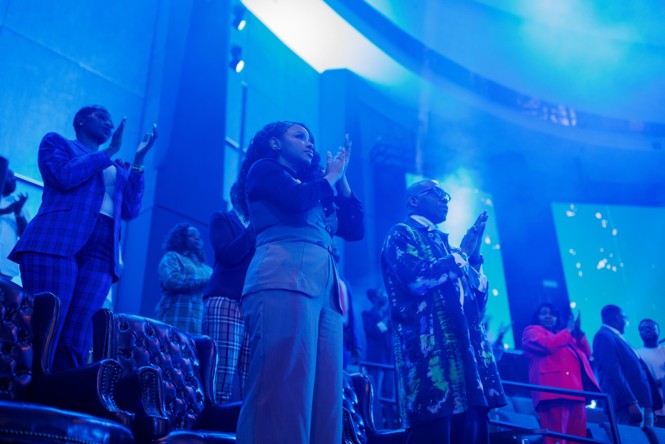 People clap in a room that is in blue light 