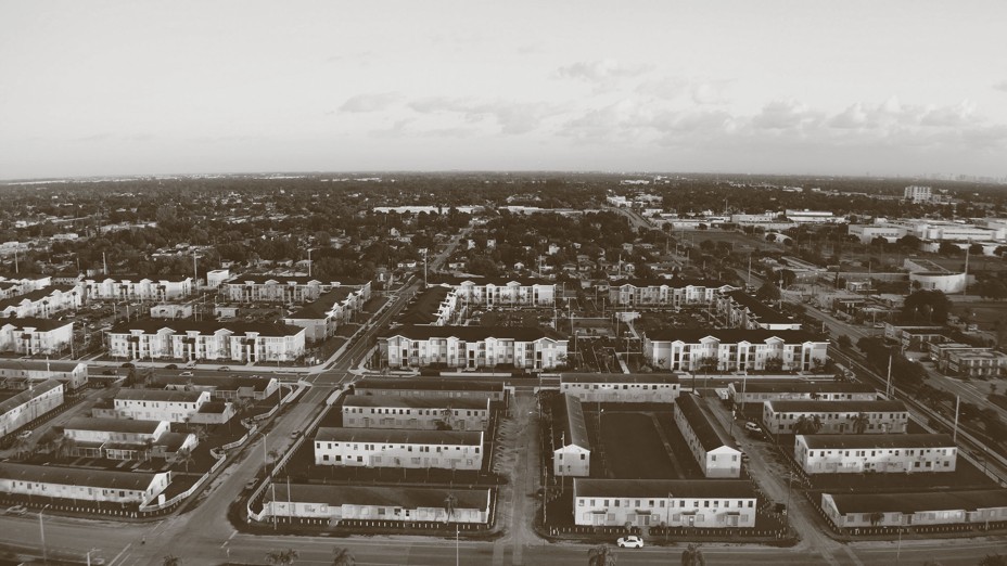 black-and-white aerial photo of neighborhood with grid of streets and white buildings with dark roofs