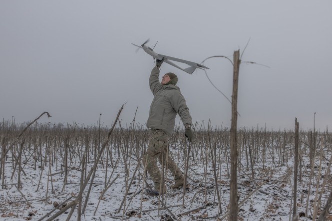 A Ukranian soldier lets a drone loose in a field