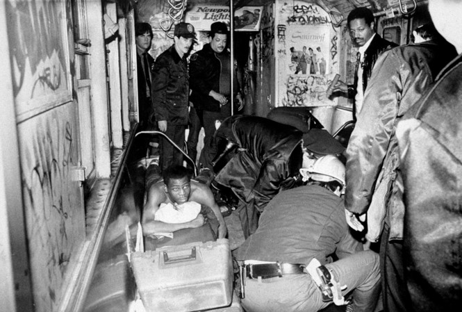 A black and white photograph showing first responders trying to help one of Goetz's victims, who is lying in the train car