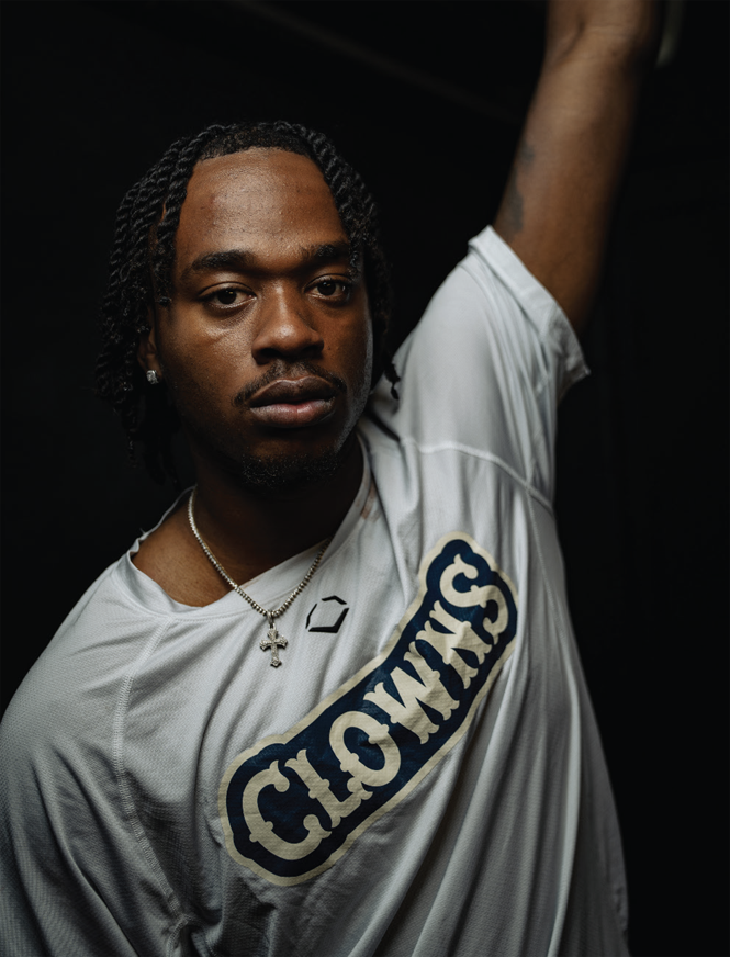 photo of man in shirt with CLOWNS logo with one arm raised