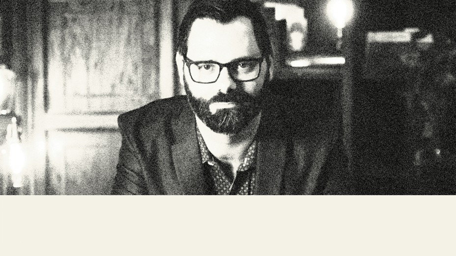 black-and-white photo of man with dark beard and glasses