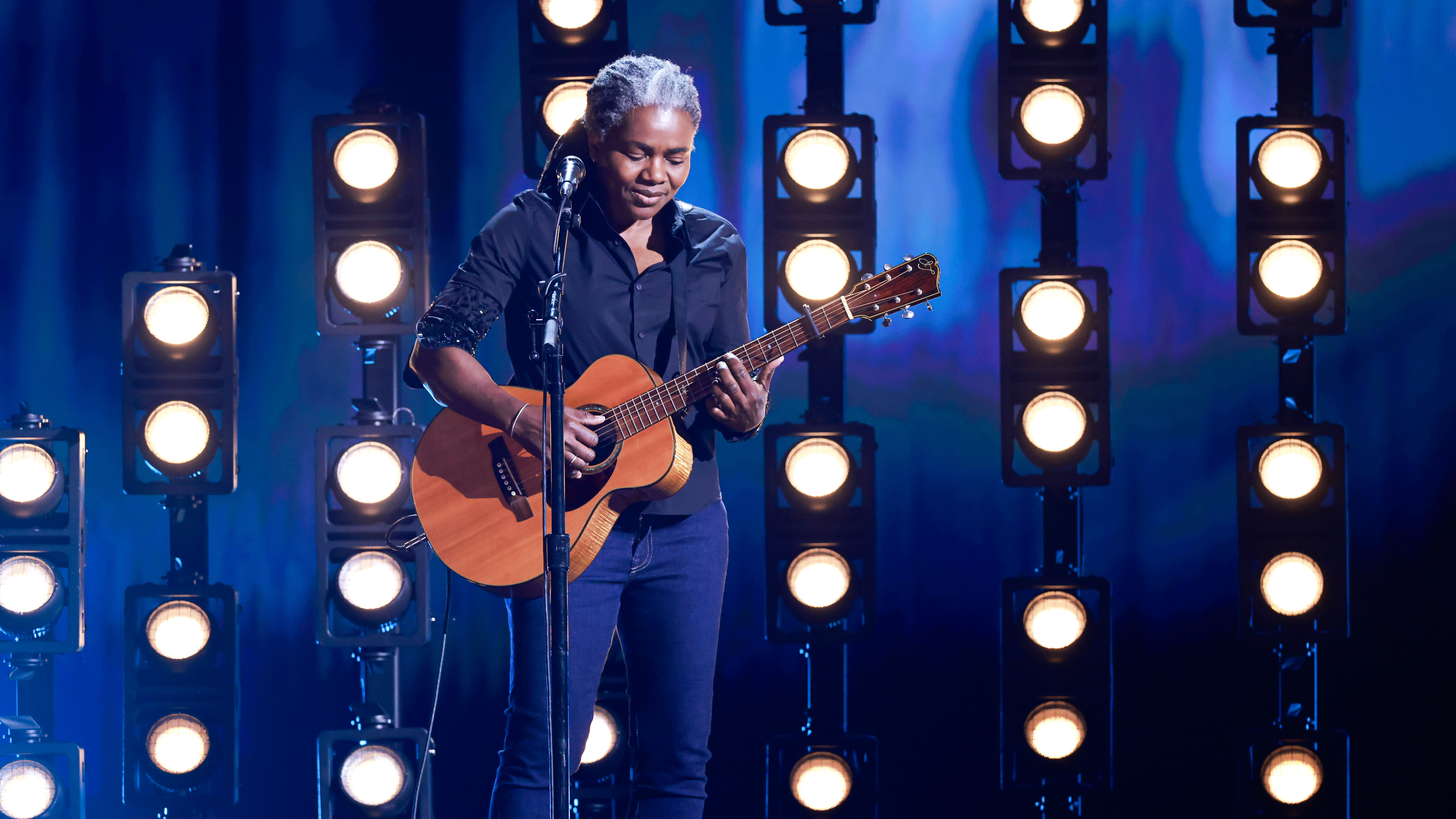 Tracy Chapman holding a guitar during her performance at the Grammys