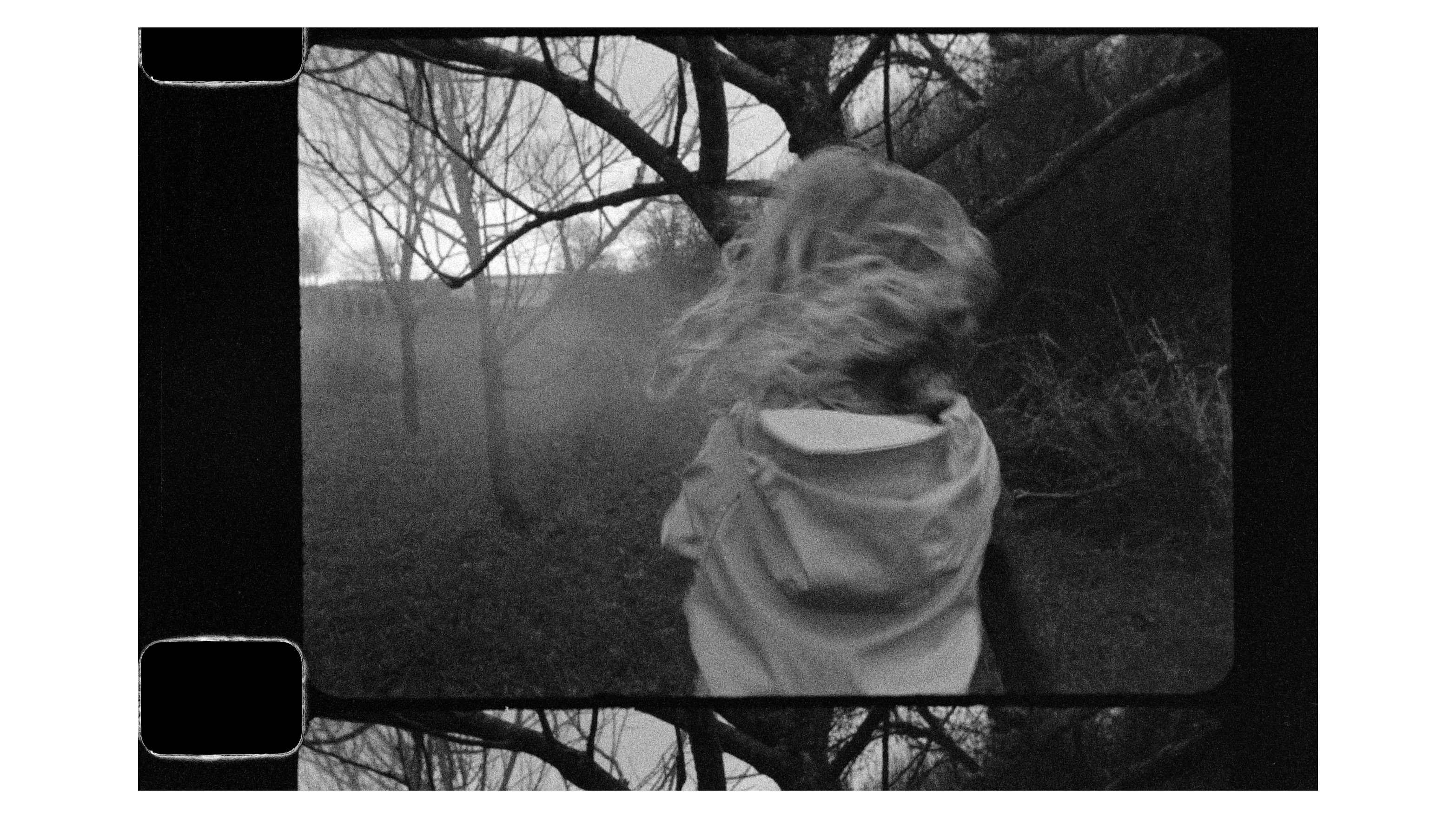 A young girl runs through a wooded area in a black-and-white photo
