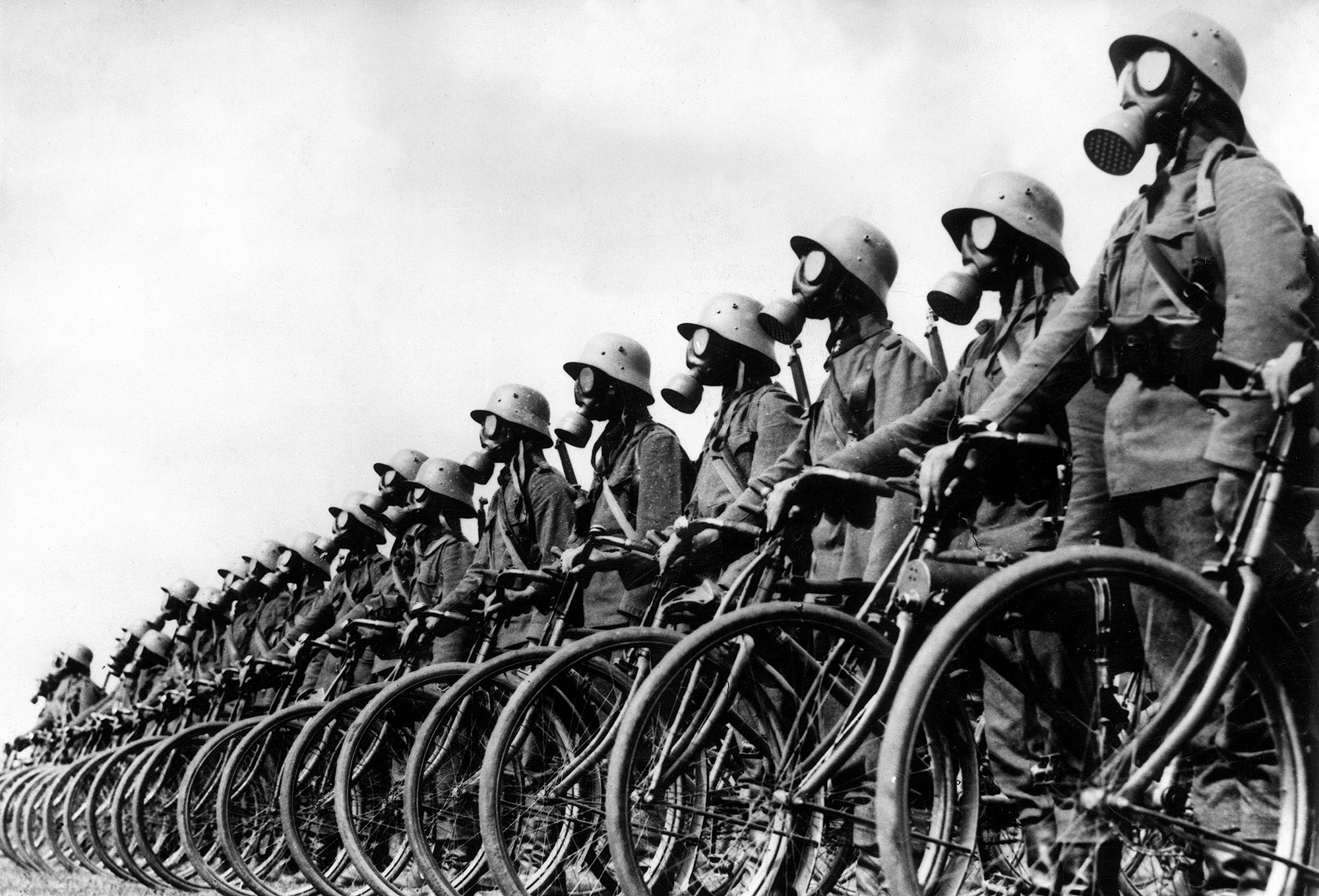 Members of the German light-machine-gun bicycle corps wear gas masks while standing beside their bicycles