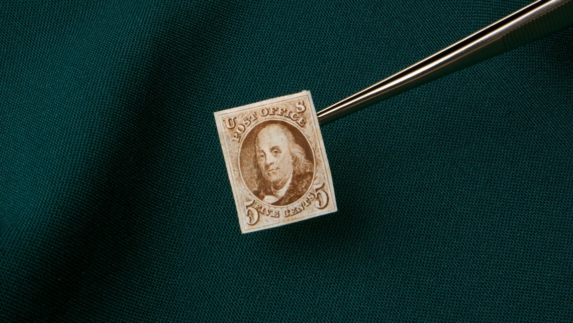 A vintage stamp held by tweezers