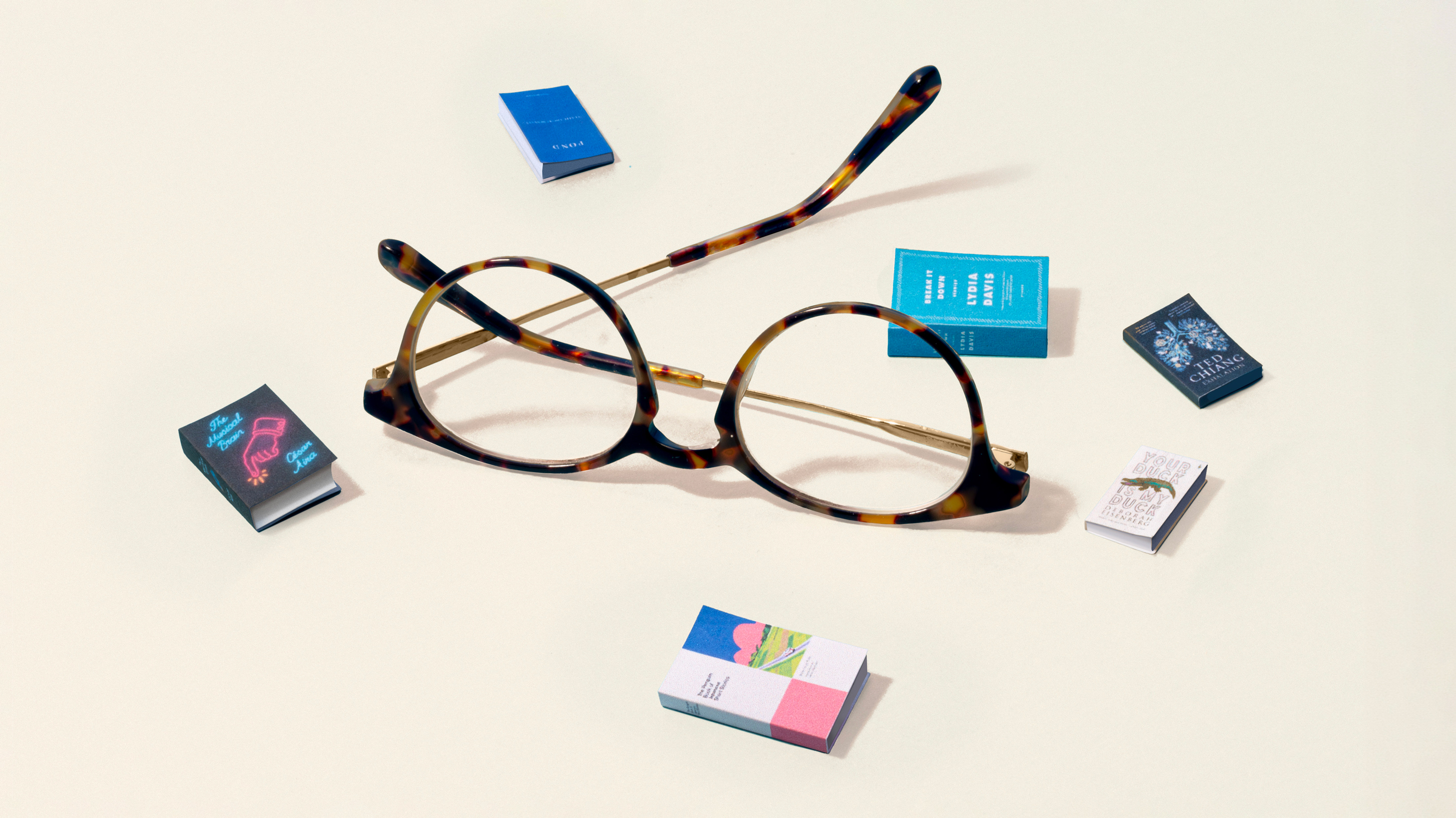 A pair of glasses rests next to different short-story book covers