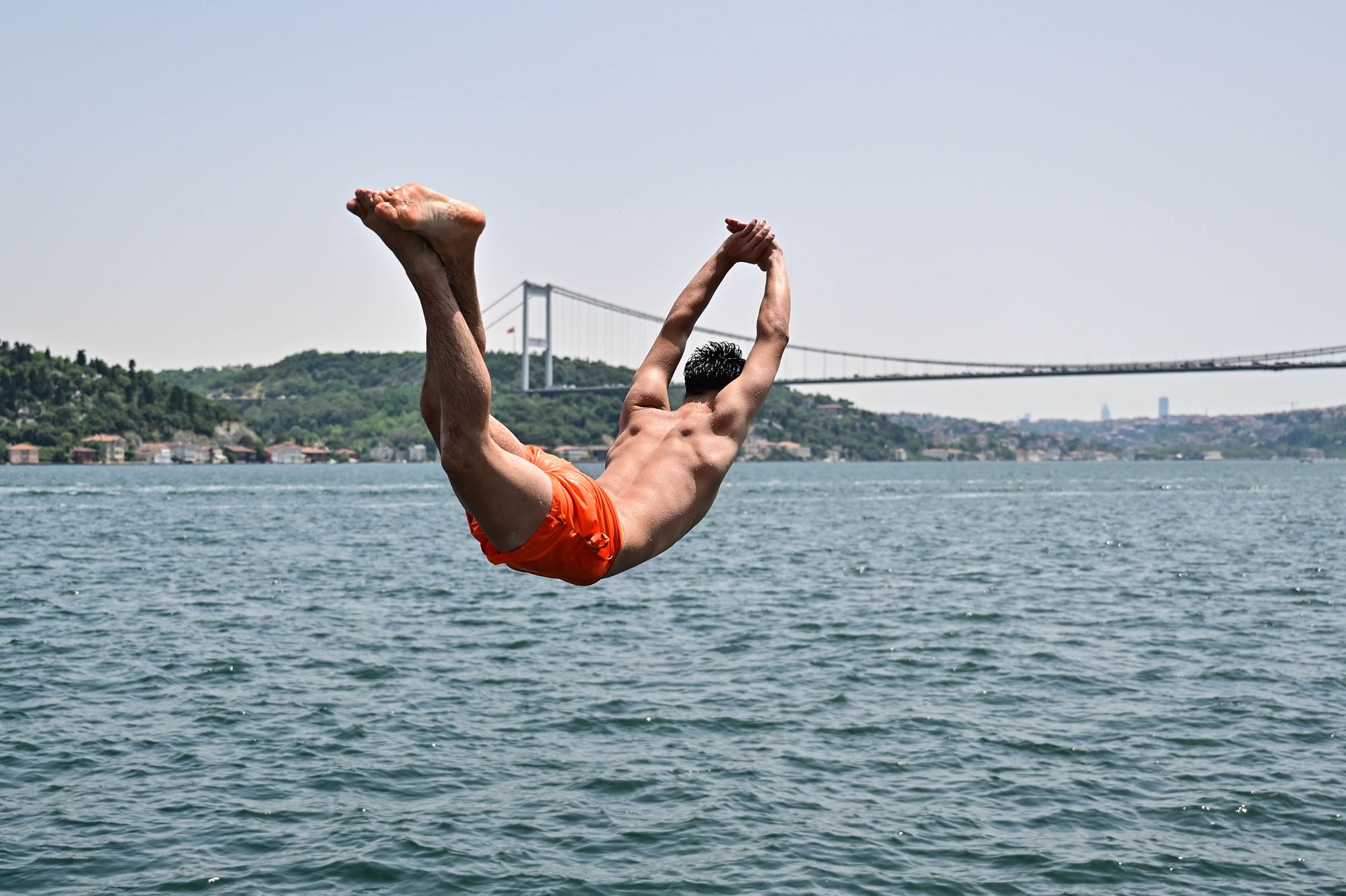 A man jumps into the sea to cool himself off during hot weather in Istanbul, Turkey.