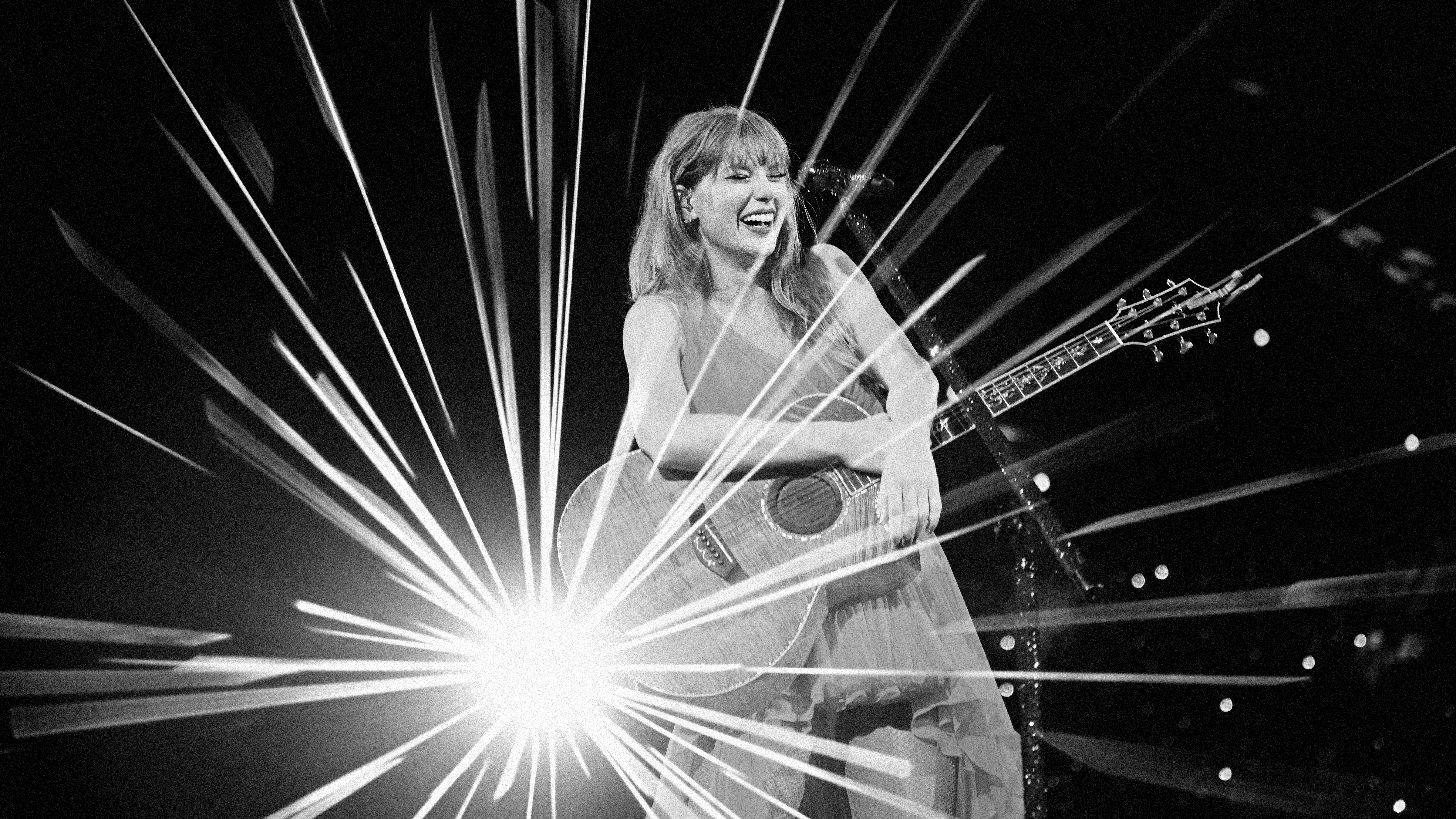 A black-and-white photo of Taylor Swift on a stage laughing