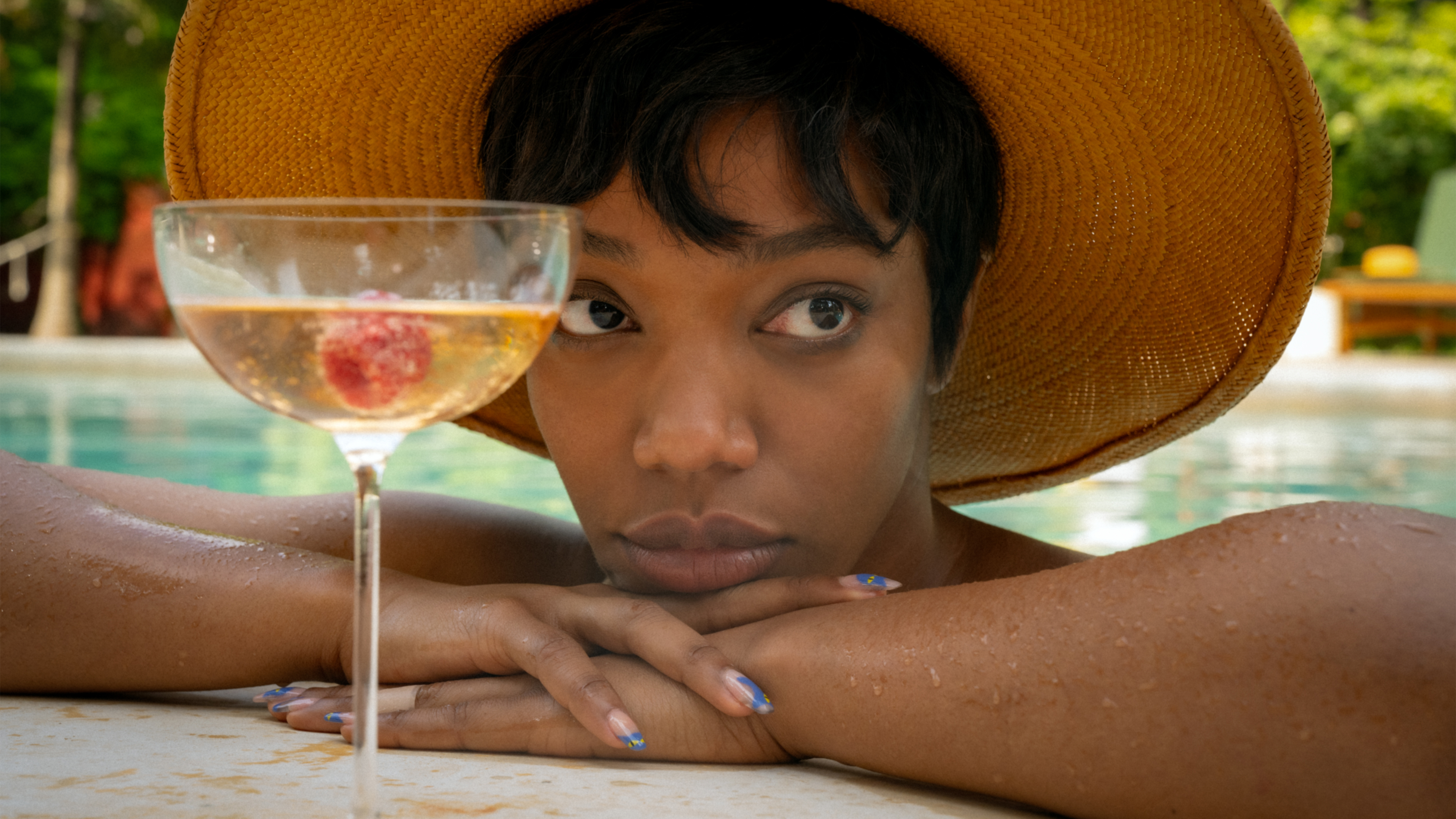 Still from Blink Twice showing a woman in a pool in front of a cocktail bar