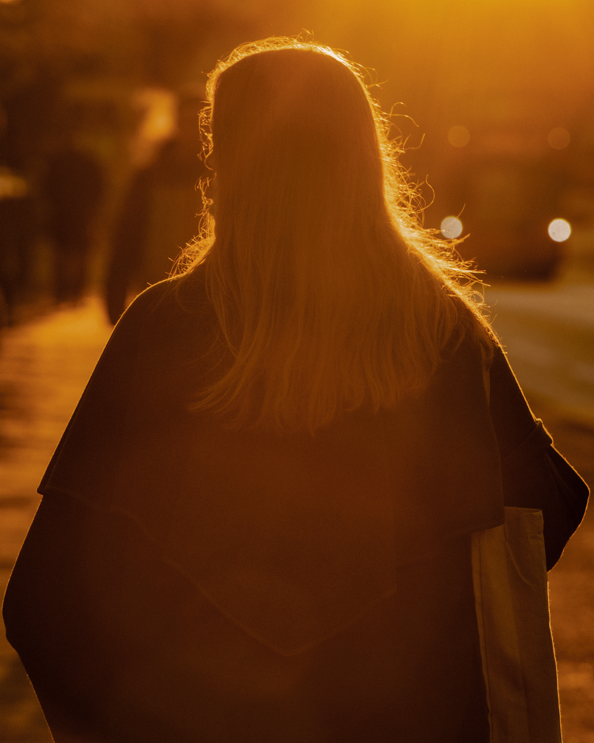 photo of long-haired woman facing away from camera and backlit by golden sunlight