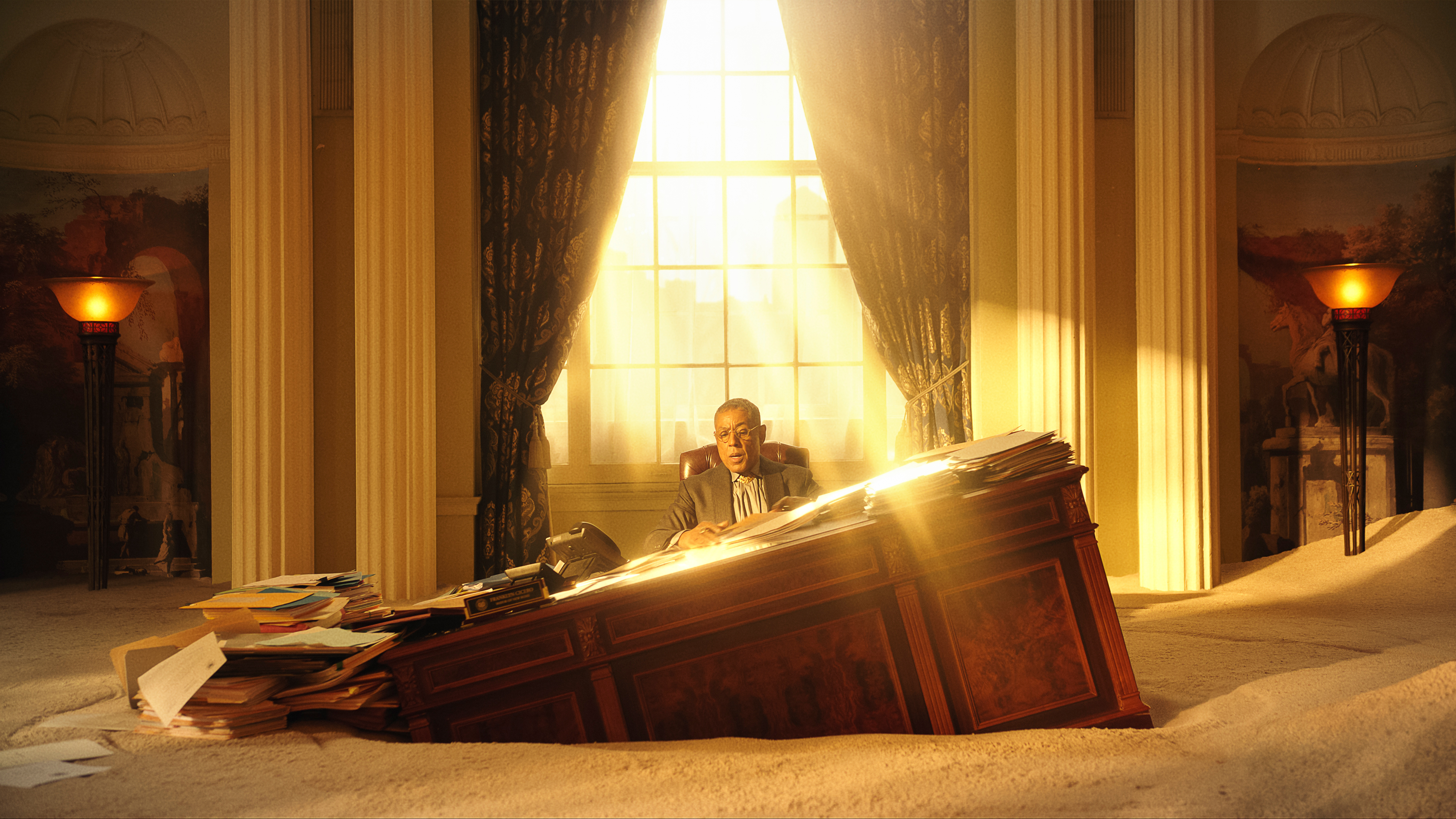 Giancarlo Esposito sits at his desk sinking into the sand