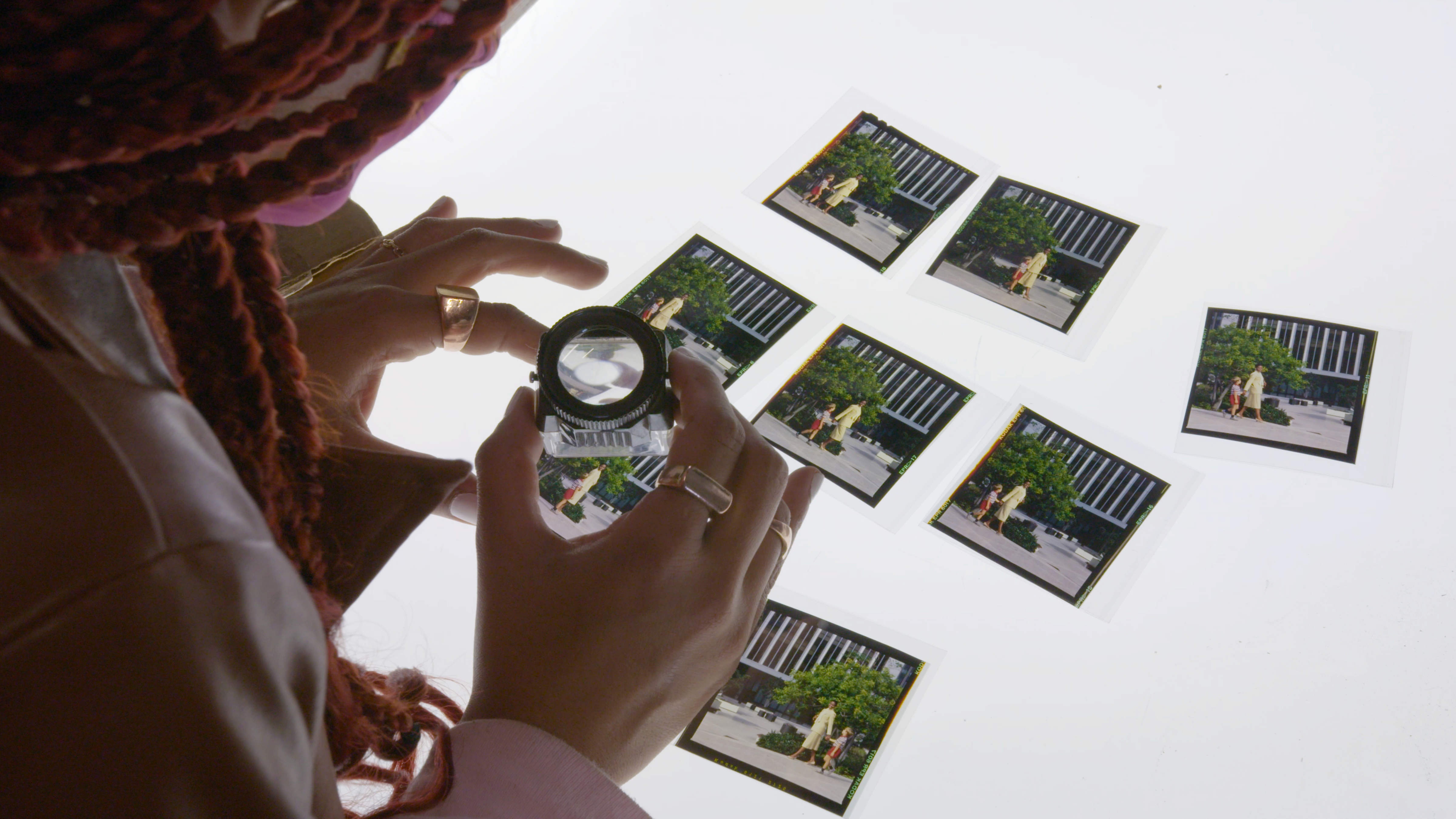 A woman holds a magnifying lens to photos