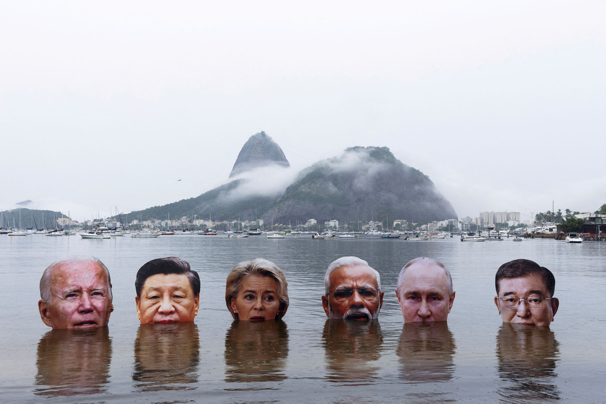 In a protest demanding action on climate change, members of Indigenous organizations hold  large cutouts of world leaders’ heads above the waters of Botafogo Bay.