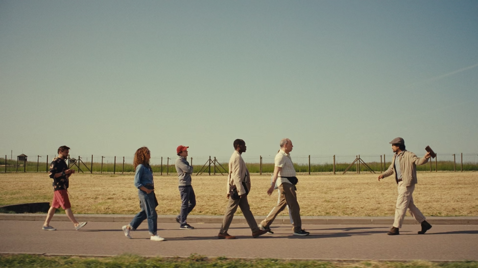 A tour that includes cousins Benji (Kieran Culkin, left) and David (Jesse Eisenberg, third from left) passes the site of a concentration camp in Eisenberg's film 