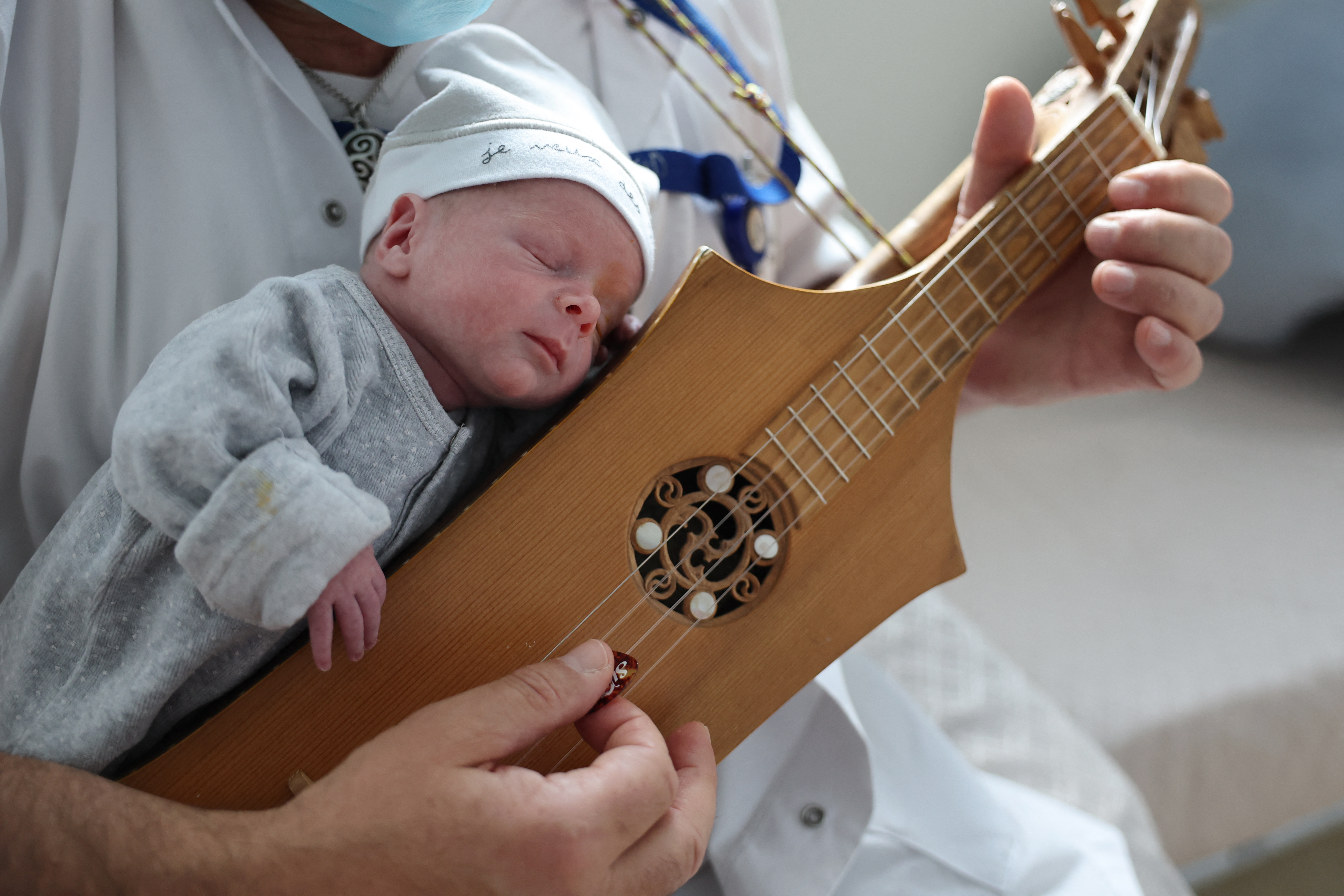 A man plays the citole for a newborn baby during a music-therapy session at the Notre-Dame de la Miséricorde hospital in Ajaccio, on the French island of Corsica.