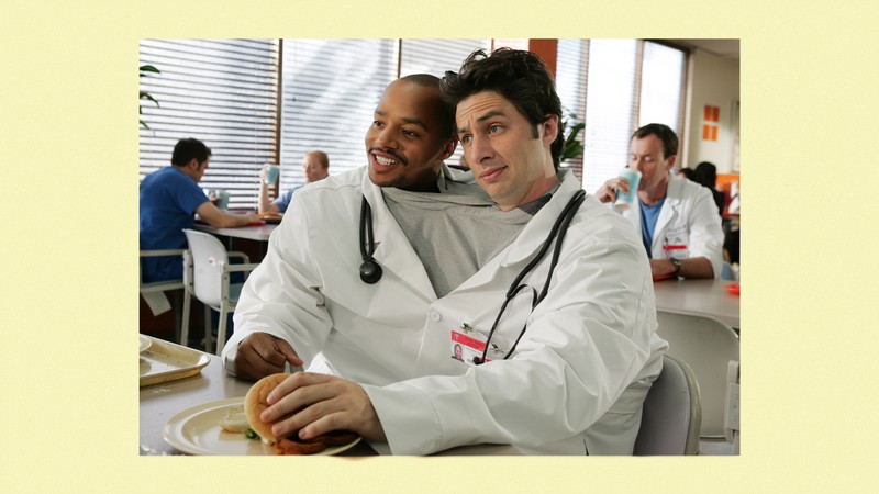 Donald Faison and Zach Braff sharing a single shirt and doctor's jacket, in a scene from "Scrubs"