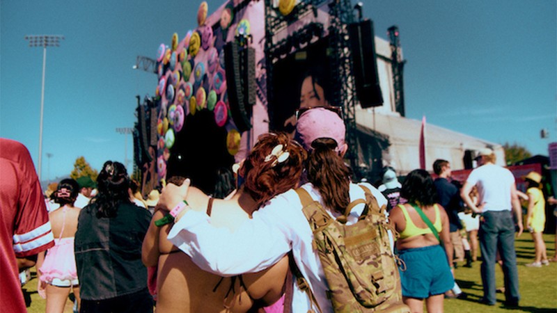 Two festival attendees face the colorful stage.
