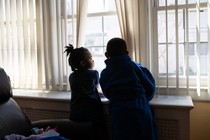 Two children look out a window