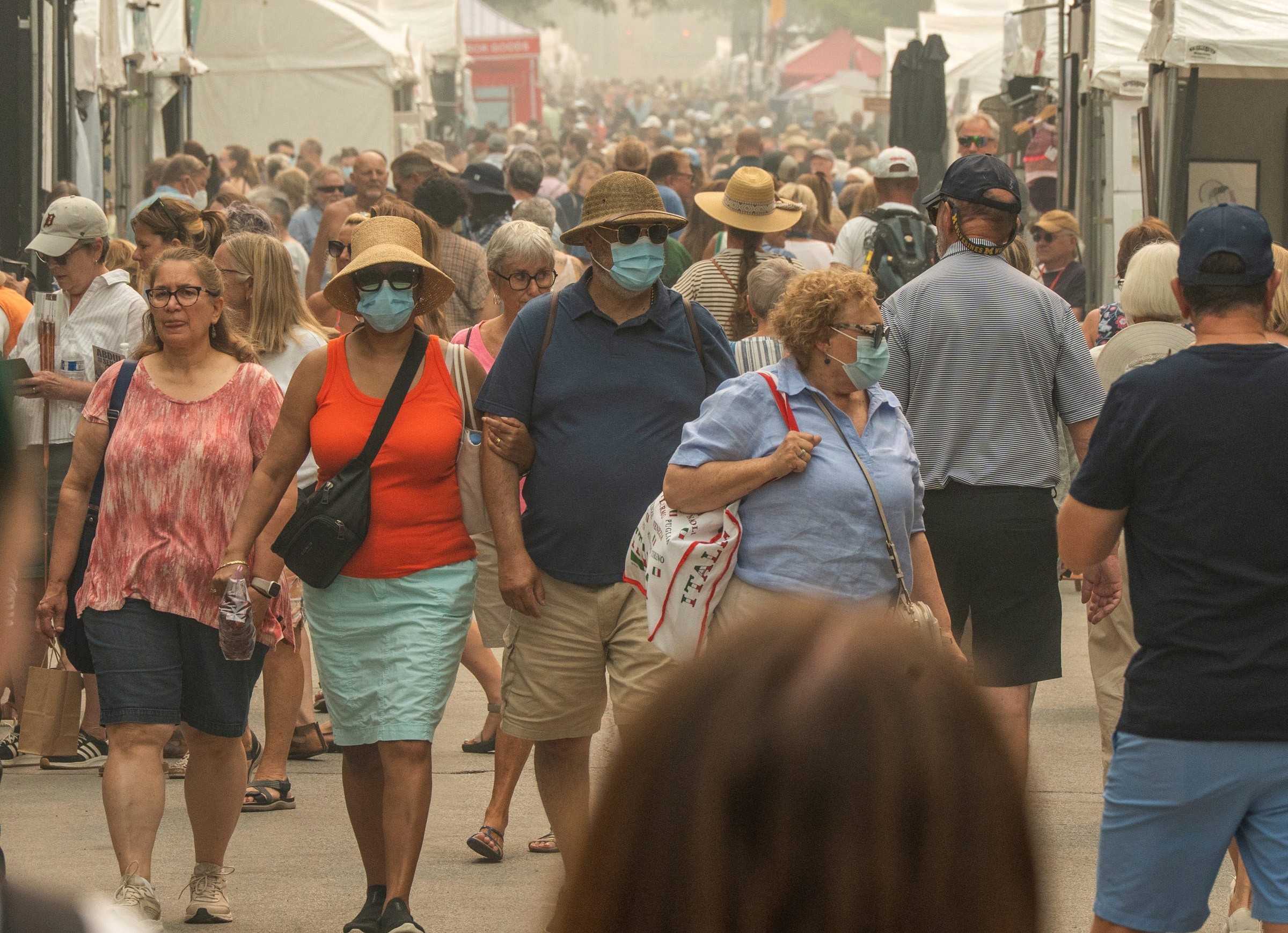 People wear masks on a hazy day at an art fair.