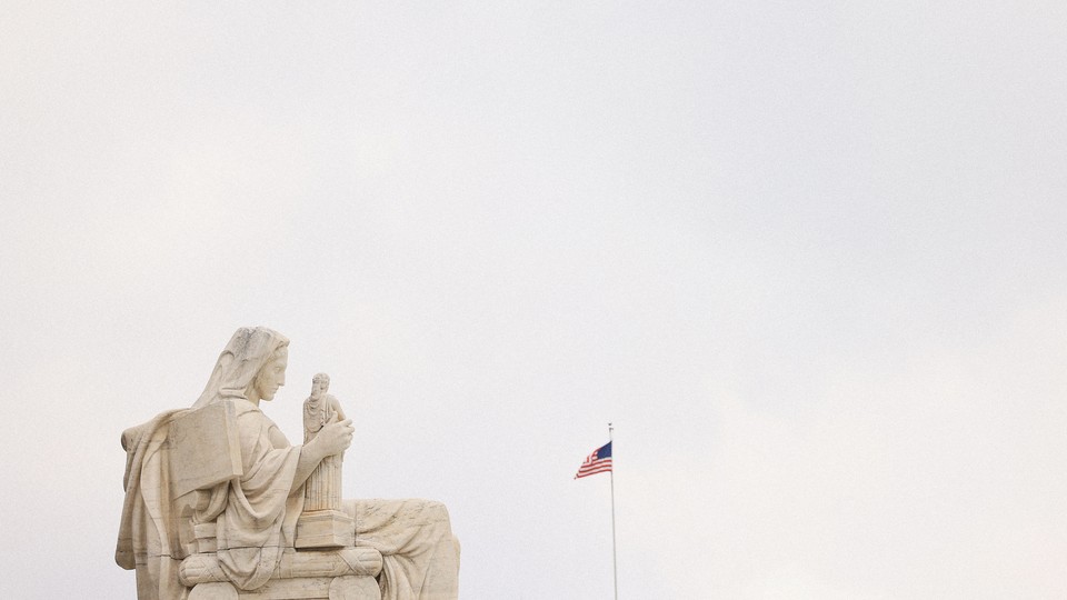 Marble statue of a woman holding a smaller marble statue in front of an American flag