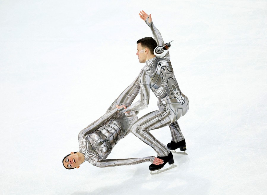 A figure-skating pair wear robotic costumes while performing on ice.