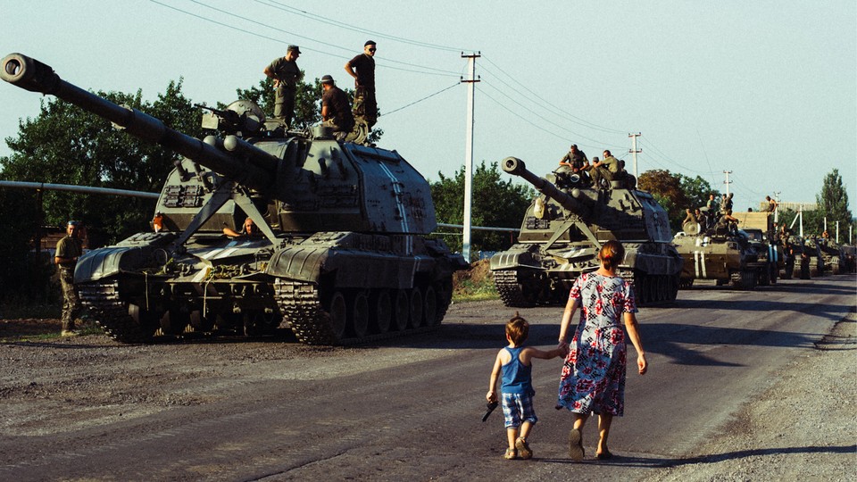 Mother and son holding hands, walking past Soviet tanks