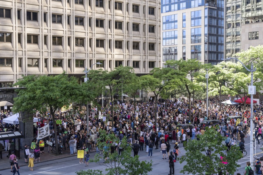 A large crowd of protesters gathers in a city square.