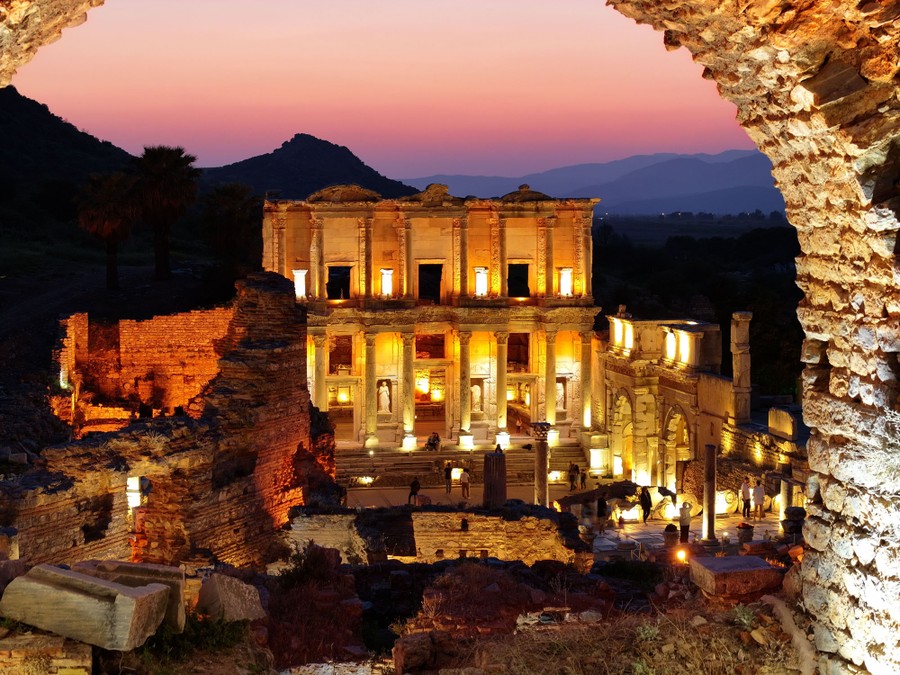Ancient ruins are lit up by modern lighting at night.