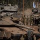 Israeli soldiers stand and walk among tanks and armored personnel carriers.