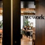 The WeWork logo is printed on a glass door, with an office visible behind it.