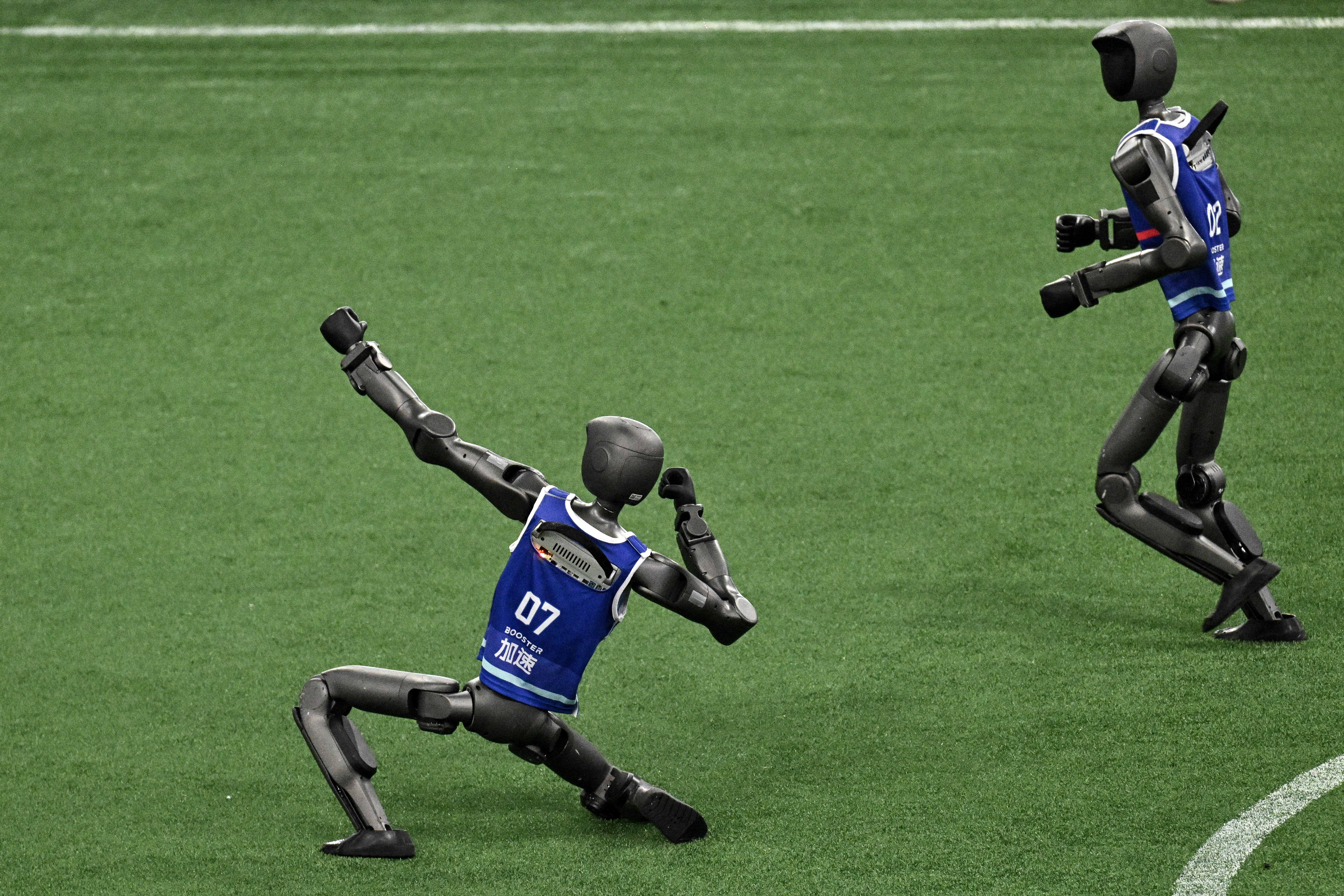 A robot strikes a pose, 'celebrating,' during a robotic soccer match.