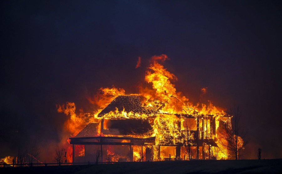 A house stands engulfed in fire at night.