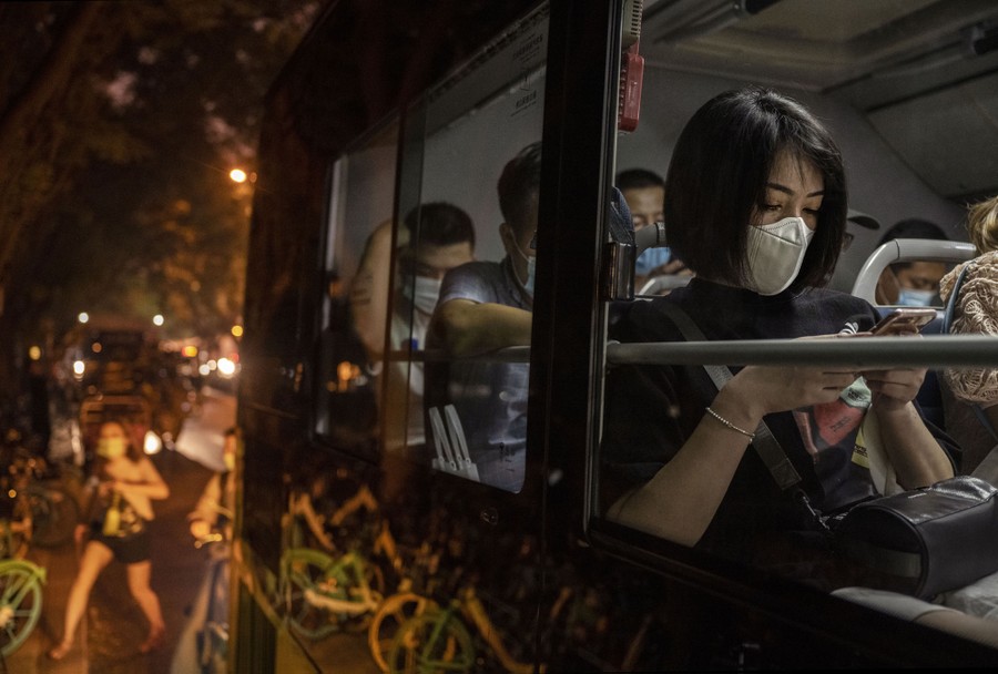 Commuters wait on a bus in Beijing at night.