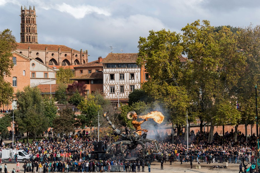 Spectators watch as a giant puppet breathes fire.