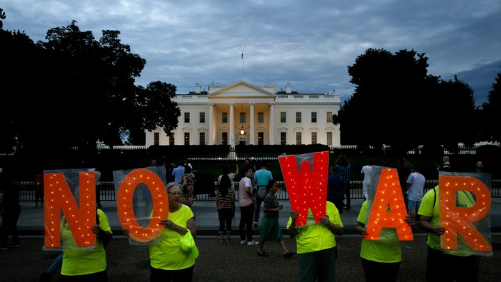 Protesters hold signs that say "No War" outside the White House on June 20.
