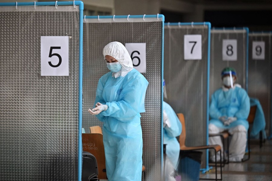 A medical worker wearing protective equipment adjusts her gloves in a testing center.