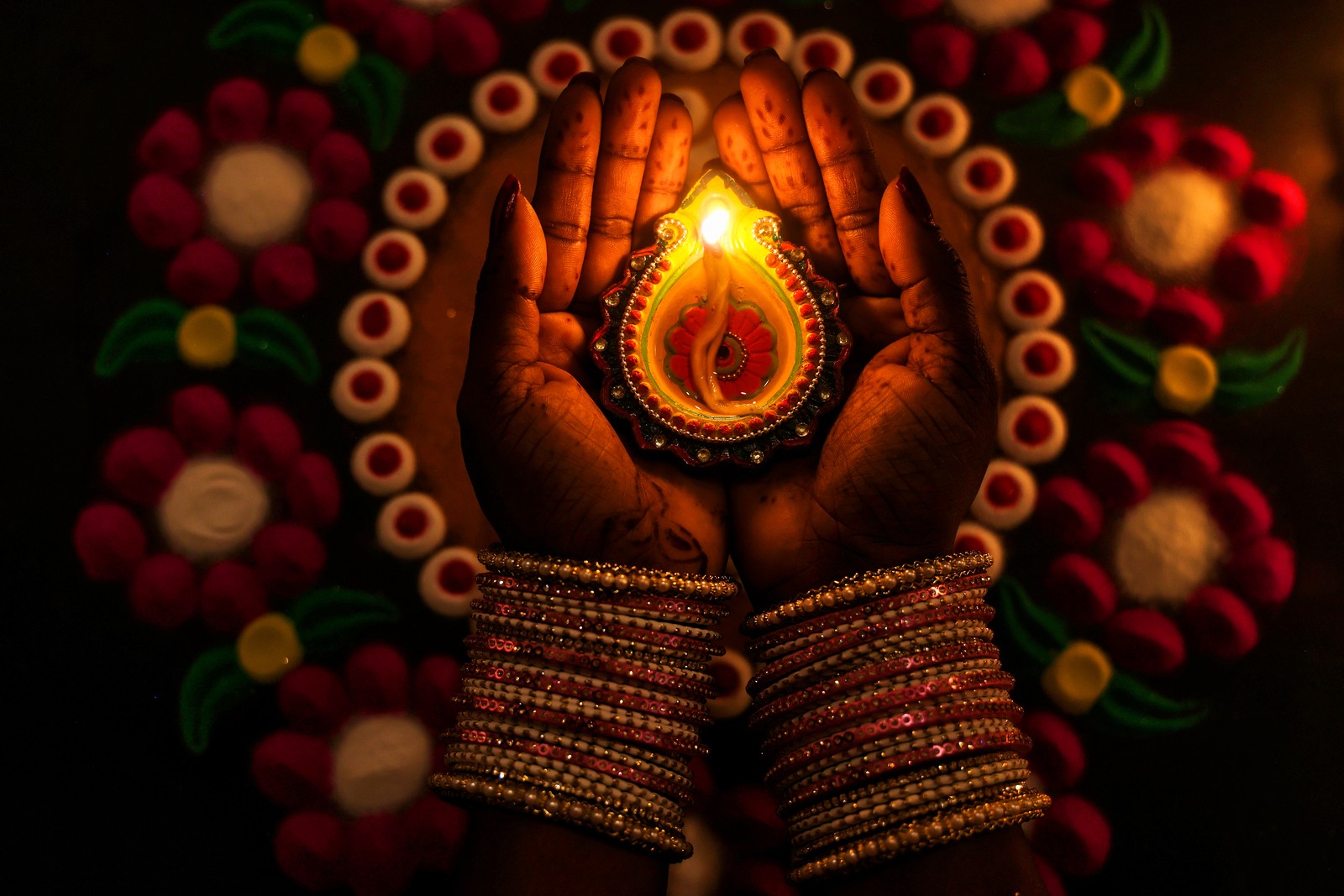 A person holding a lit oil lamp in their hands.