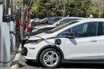 Photo of a row of cars, plugged into charging stations