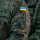Photograph of Ukrainian flag patches on the arms of uniformed soldiers.