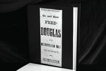 A photograph of a blank book cover with a projection of vintage text on top.